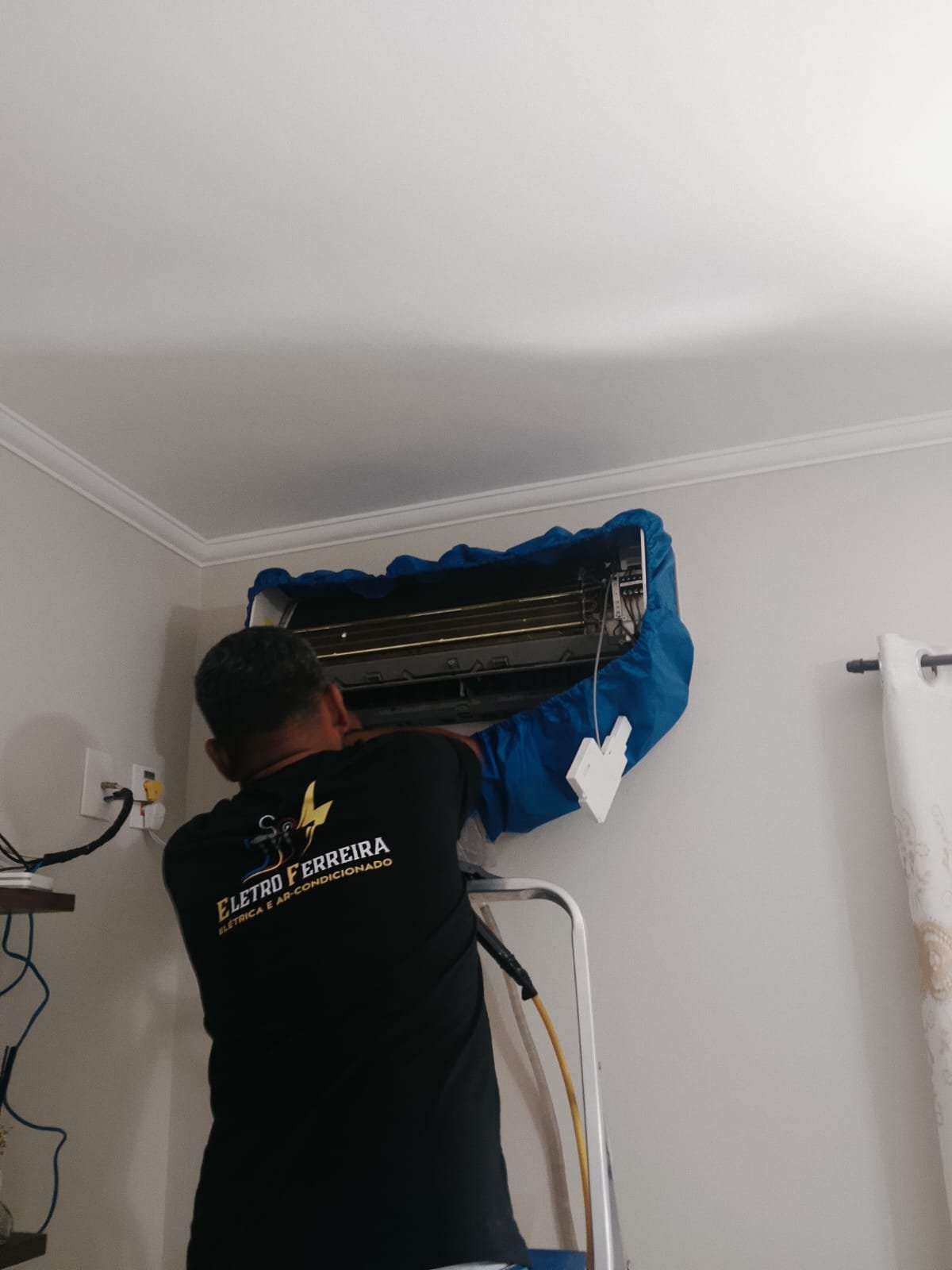 Técnico Eletro Ferreira realizando serviço de ar-condicionado